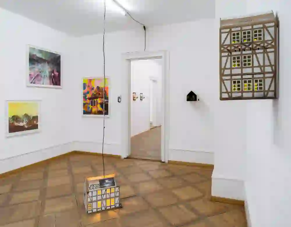 Das Foto ist eine  Aufnahme aus dem Kunsthaus Langenthal, welche eine Ausstellung der Künstlergruppe "Courtesy of the Artists" zeigt. Die Ausstellung wirkt dynamisch und zeitgenössisch, mit lebendigen Farben und unterschiedlichen Medien, die im Raum verteilt sind.