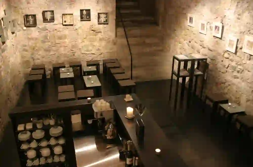 The picture shows the atmospheric interior of the ONO cultural venue in Bern, with art on the stone walls and elegantly arranged tables that provide a cosy and creative ambience for guests.