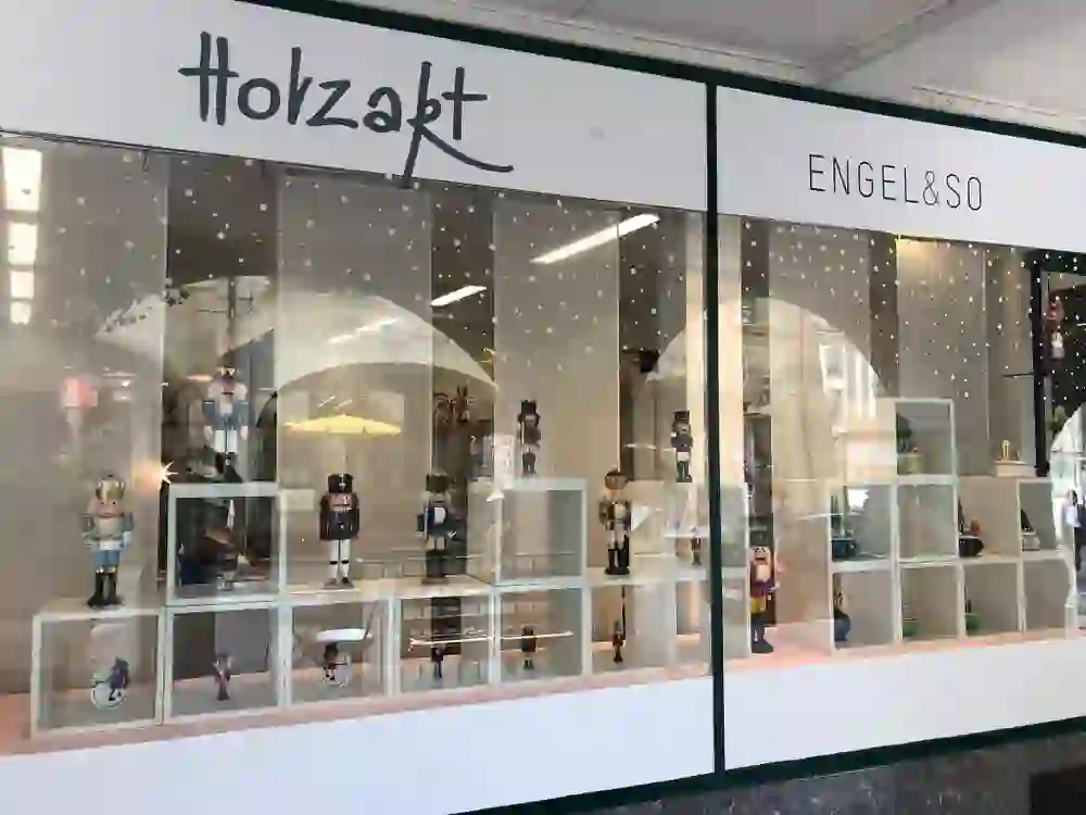The picture shows the Holzart shop window, which presents a variety of colourful, handmade wooden figures. The playful arrangement and clear design invite you to linger and discover, creating a cheerful and creative atmosphere.