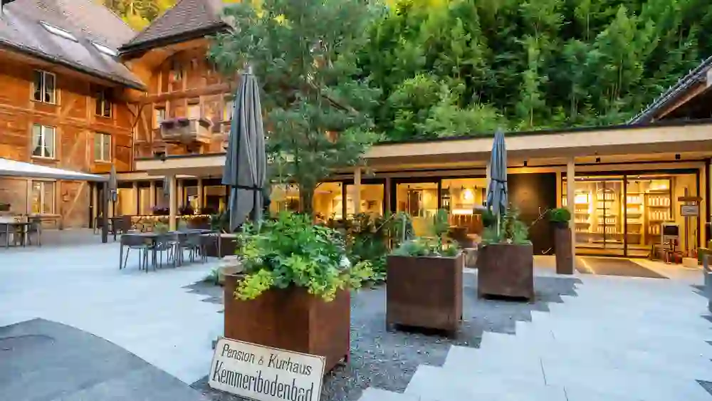 Das Bild zeigt das Hotel Kemmeriboden-Bad, eingebettet in eine malerische Landschaft mit einem lebendigen Außenbereich, der eine herzliche und einladende Atmosphäre inmitten der Natur ausstrahlt.