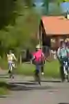 Une joyeuse famille de cyclistes entourée d'une verdure luxuriante et d'une maison traditionnelle - une image d'idylle rurale et de loisirs partagés.