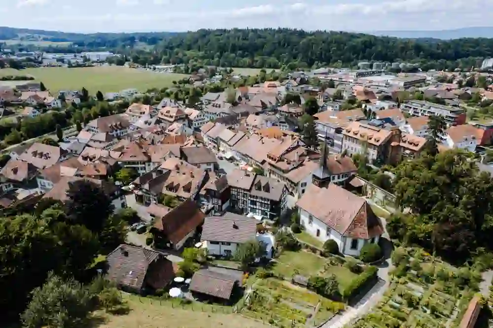 La ripresa con il drone di Laupen rivela una pittoresca cittadina svizzera immersa in un paesaggio lussureggiante, un mosaico di tetti storici e vita moderna, pieno di fascino pacifico.