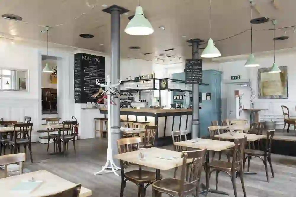 Das Bild zeigt das Innere eines stilvollen Restaurants mit einer entspannten und gemütlichen Atmosphäre. Die Kombination aus Vintage-Möbeln, Tafelmenüs und sanfter Beleuchtung schafft ein einladendes Ambiente, das zum Verweilen und Genießen einlädt.