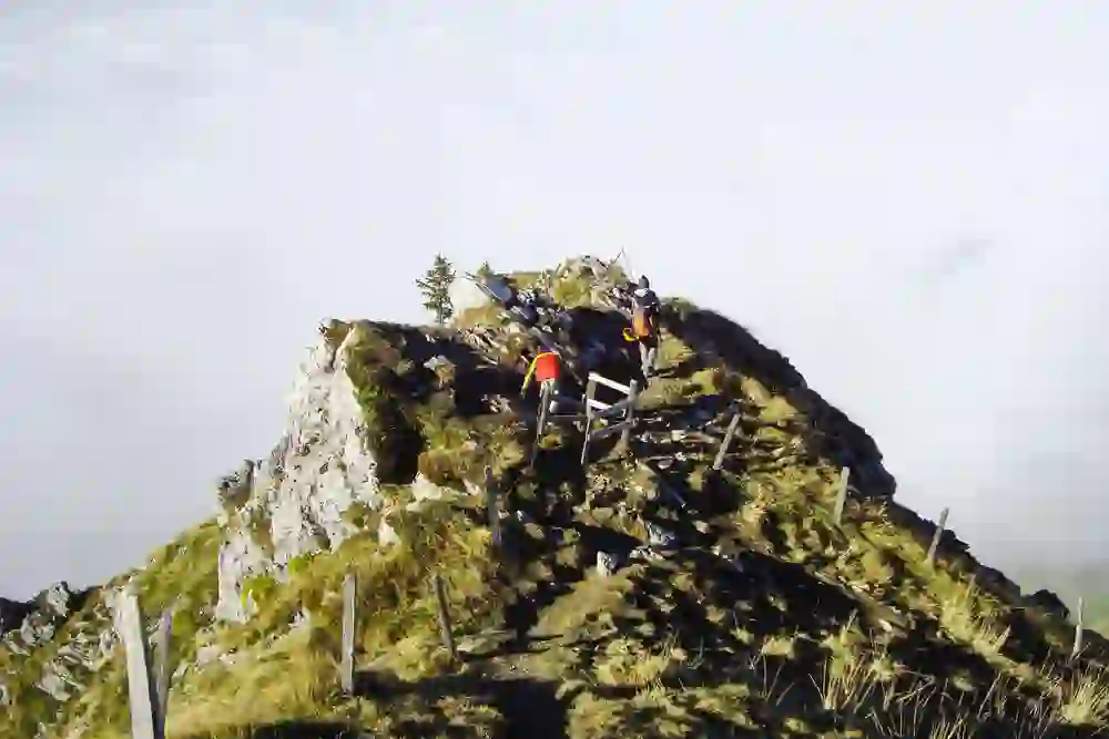 Das Bild zeigt Wanderer auf einem Klettersteig im Naturpark Gantrisch. Umgeben von einem Meer aus Wolken, erklimmen sie mit sichtbarer Entschlossenheit und Konzentration den felsigen Pfad, die Weite der Natur geniessend. Ein Gefühl von Abenteuer und Freiheit durchzieht die Szene.