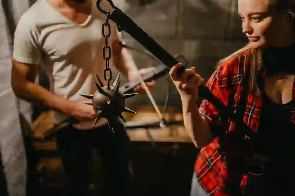 I giocatori esaminano un'arma medievale nella Mastermind Escape Room di Berna, presi da un momento di fascino e di intensa concentrazione sul puzzle che hanno davanti.