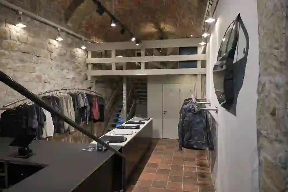 Das Bild zeigt den Innenraum des ST. VIR-Geschäfts, der mit seinem rohen Mauerwerk und der modernen Einrichtung eine stimmungsvolle Kombination aus historischem Charme und zeitgenössischem Design darstellt.