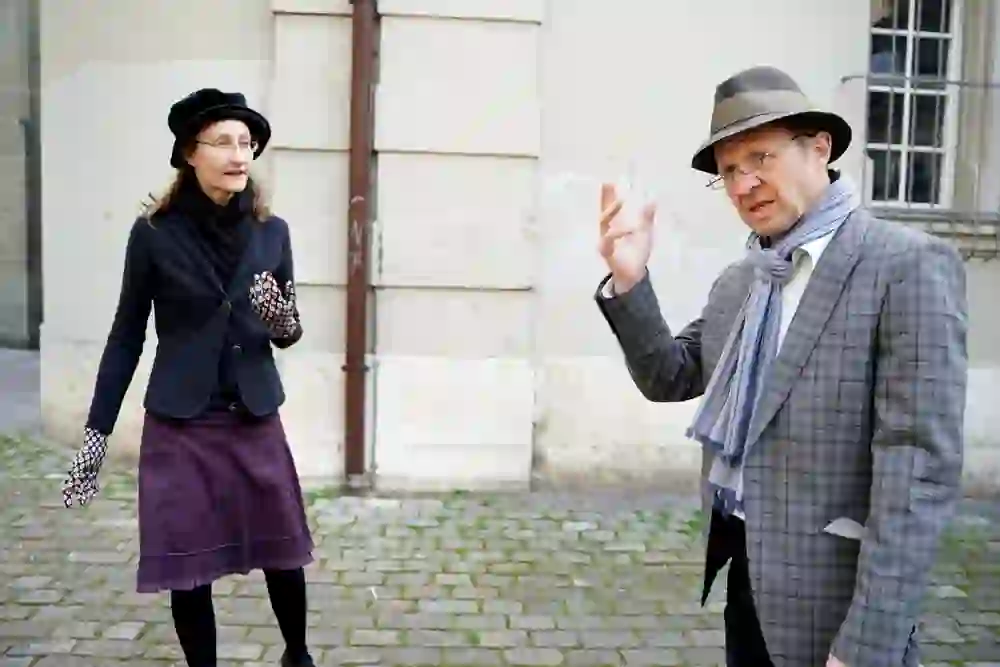 Zwei Stadtführer, stilvoll in traditionelle Kostüme gekleidet, geben mit lebhafter Gestik und fesselnder Mimik Einblicke in das Labyrinth Dürrenmatts.