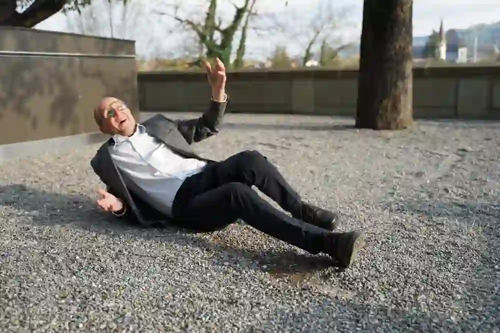 Una guida della città si sdraia teatralmente sulla ghiaia mentre rievoca una scena del Labirinto di Dürrenmatt con gesti espressivi e visibile vigore.