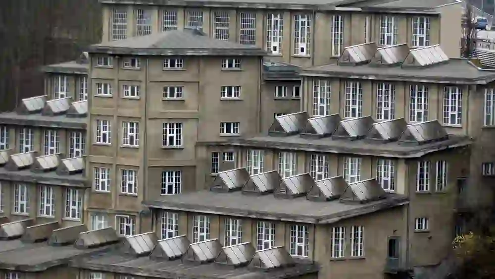 L'immagine mostra l'impressionante vista esterna della location per eventi Stufenbau, la cui caratteristica architettura a gradoni e le numerose finestre creano un'estetica geometrica. La facciata grigia e la disposizione strutturata degli elementi conferiscono all'edificio un aspetto serio e solido.