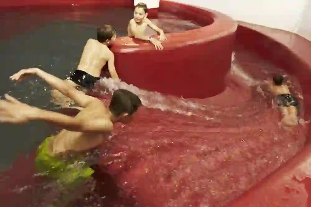 Children full of joy and energy slide and play in a rotating whirlpool; their faces show exuberance and pleasure.