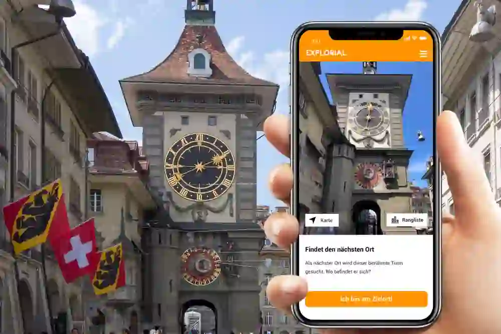 La foto mostra una persona che tiene in mano uno smartphone e scatta una foto dello Zytglogge di Berna. L'applicazione per cellulari è una sorta di guida turistica o di città per un tour interattivo in cui gli utenti navigano in vari luoghi.