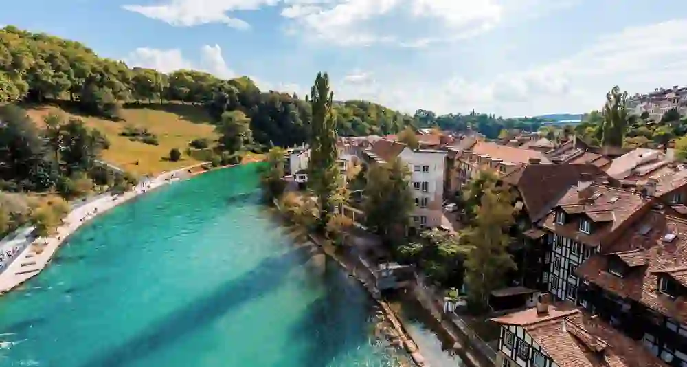 The Aare meanders briskly through Bern, past the traditional houses and green banks, a picture of summery lightness and urban harmony with nature under an expansive sky.