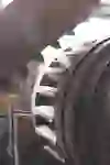 Close-up of an old wooden mill wheel mechanism with visible gears and beams showing the textures of weathered wood and metal parts.