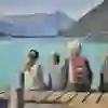 Eine Großmutter sitzt mit drei Kindern auf einem Steg am türkisblauen See, umgeben von majestätischen Bergen. Der Moment strahlt Ruhe, Geborgenheit und die Schönheit der Natur aus – ein harmonisches Bild von Familie und Entspannung in einer traumhaften Kulisse.