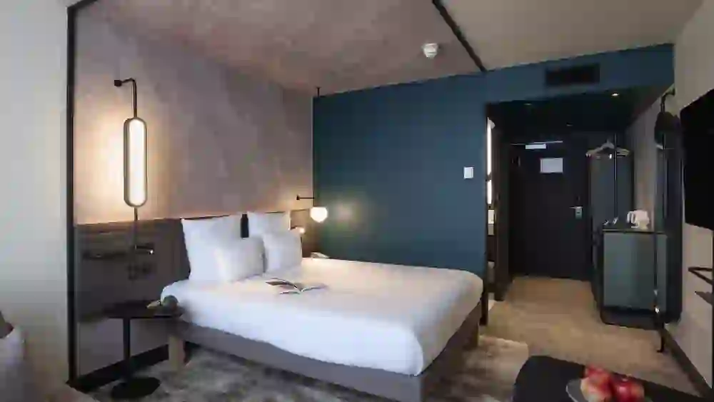 L'immagine mostra una camera moderna ed elegantemente arredata del Novotel Bern Expo. Con il suo design semplice e l'illuminazione soffusa, irradia calma e invita a soffermarsi in un'atmosfera di eleganza urbana.