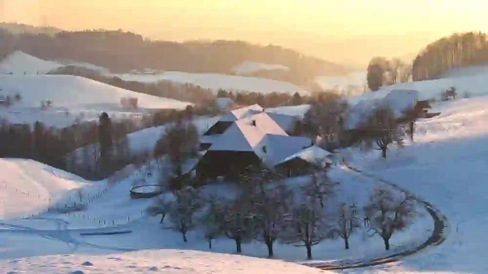 Auf dem Bild ist eine verschneite Landschaft im Emmental zu sehen.