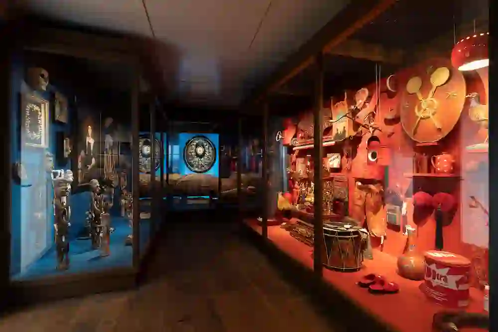 Das Bild zeigt eine eindrucksvolle Ausstellung im Museum Schloss Burgdorf mit zwei farbintensiven, thematischen Vitrinen. Die linke, in Blautönen, präsentiert mysteriöse Artefakte und Schädel, während die rechte Vitrine in warmem Rot kulturelle Gegenstände zur Schau stellt, was ein spannendes und lebendiges Ambiente erzeugt.