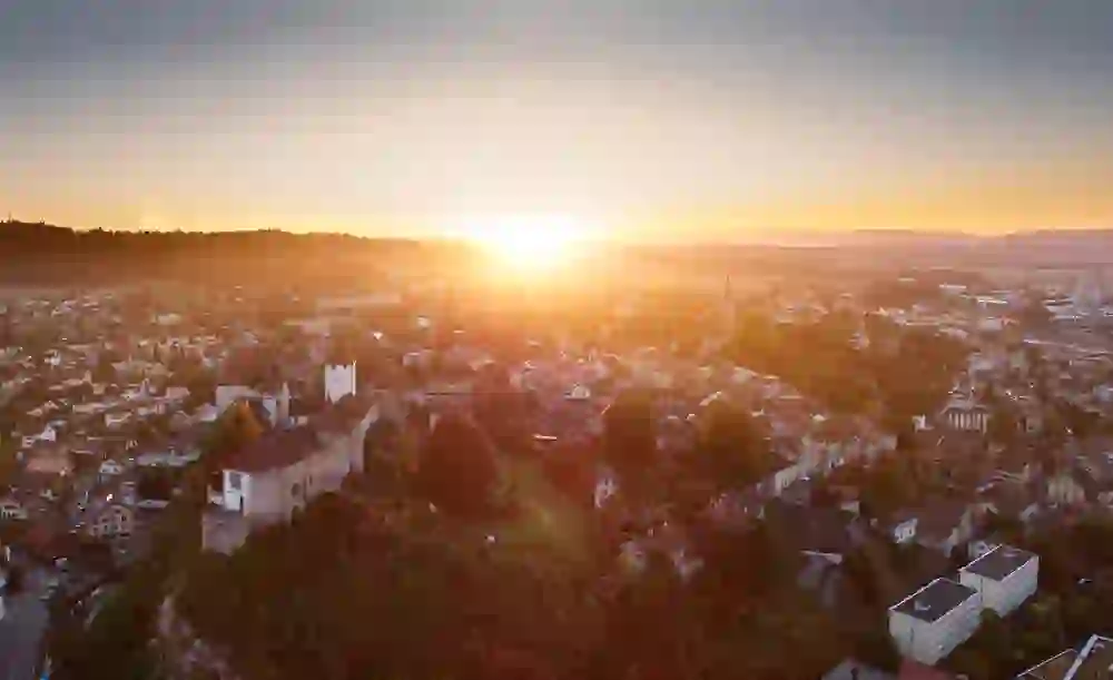 The sunset bathes Burgdorf Castle and the surrounding town in golden colours, creating a peaceful, picturesque scene.
