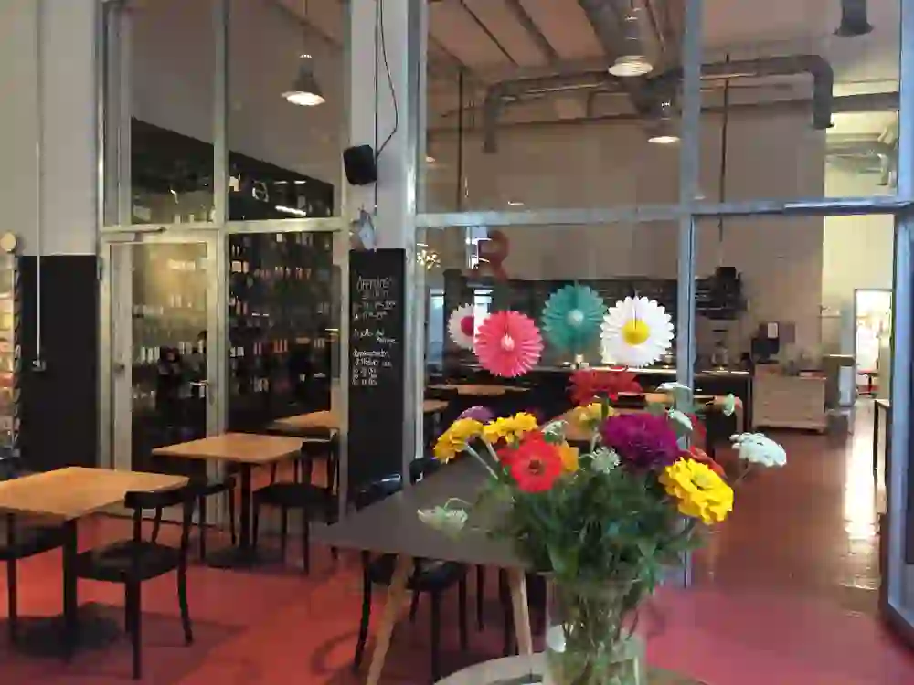 The picture shows the bright, industrial-style restaurant le beizli with colourful flowers and wall decorations, which conveys a lively and friendly atmosphere.