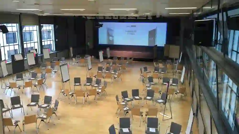 Une salle de conférence avec des chaises et des flipcharts dispersés. L'environnement préparé mais vide attend un événement ou un atelier interactif.