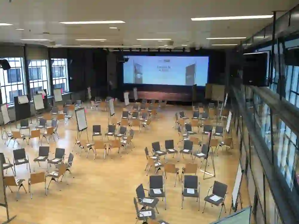 Une salle de conférence avec des chaises et des flipcharts dispersés. L'environnement préparé mais vide attend un événement ou un atelier interactif.