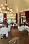L'immagine mostra la luminosa sala da pranzo della Josephine Brasserie dell'Hotel Unique Innere Enge, che trasmette una sensazione di classica eleganza e distinta ospitalità con i suoi eleganti lampadari e i pittoreschi murales.