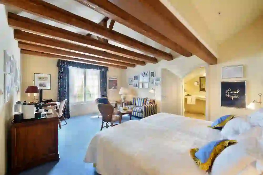 Das Bild zeigt ein geräumiges, helles Zimmer im Unique Hotel Innere Enge in Bern mit sichtbaren Holzbalken und stilvoller Einrichtung, die eine Atmosphäre von Komfort und traditioneller Eleganz vermittelt.