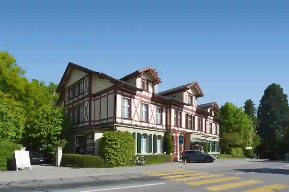The photo shows a traditional half-timbered house under a blue sky, capturing the warm and welcoming atmosphere of the Unique Hotel Innere Enge.