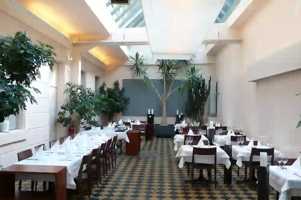 The photo shows a bright and airy restaurant with elegant table decorations and plants that create a relaxed and inviting atmosphere.