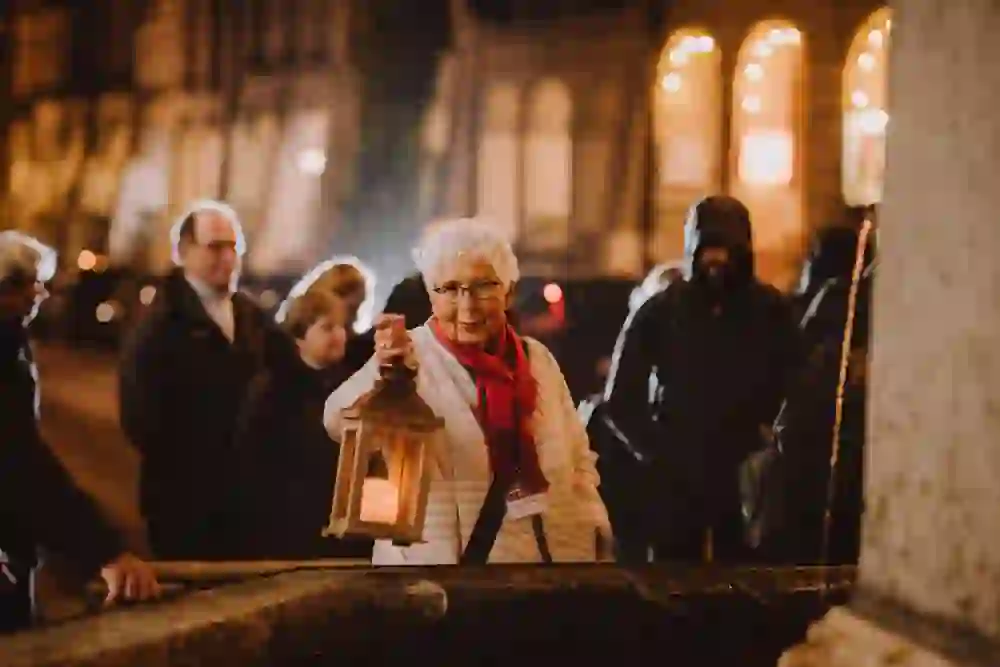 Una guida della città di Berna tiene in mano una lanterna e aggiunge un tocco di nostalgia spettrale alla visita notturna. I suoi occhiali riflettono la luce calda mentre cattura gli sguardi in attesa.