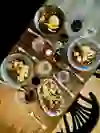 La photo montre une scène de table rustique au restaurant Sua à Berne, avec des plats et du vin disposés avec goût, créant une ambiance détendue et conviviale pour un repas savoureux entre amis.
