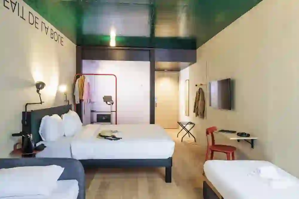 The picture shows two people in a lively pillow fight in a stylish hotel room at the Hotel Ibis Styles Bern City. The room radiates joy and activity, emphasised by the modern furnishings and bright lighting.