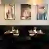 Das Bild zeigt eine stilvolle Ecke im Restaurant Bonbec. Die schlichte Einrichtung mit dunklem Mobiliar, edlen Weingläsern und dezentem Kerzenlicht schafft eine ruhige, elegante Atmosphäre. An den Wänden hängen kunstvolle Fotografien, die dem Raum eine persönliche Note verleihen. Ideal für ein entspanntes Dinner in moderner, urbaner Umgebung.
