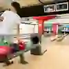 A young player at the Marzili Bowling Centre concentrates on his ball, ready for his next throw, while the game is in full swing in the background.