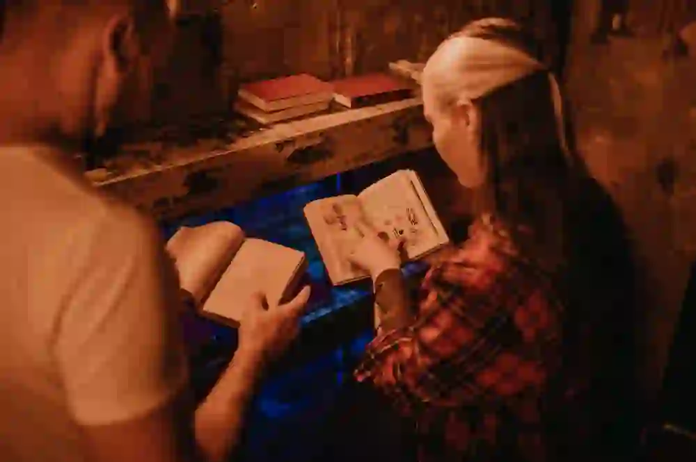 Auf dem Foto ist ein Paar in einem Escape Room vertieft in Bücher. Die warme Beleuchtung schafft eine geheimnisvolle Atmosphäre, während sie gemeinsam nach Hinweisen suchen. Ihre konzentrierten Gesichtsausdrücke und die flackernde Umgebung vermitteln ein Gefühl von Spannung und Teamwork.