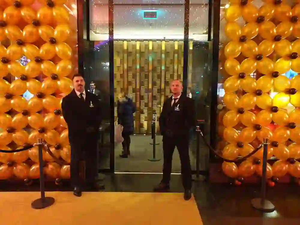 Ricevimento elegante con palloncini dorati e portieri in giacca e cravatta. L'atmosfera è esclusiva e festosa: la serata promette glamour e buon umore.