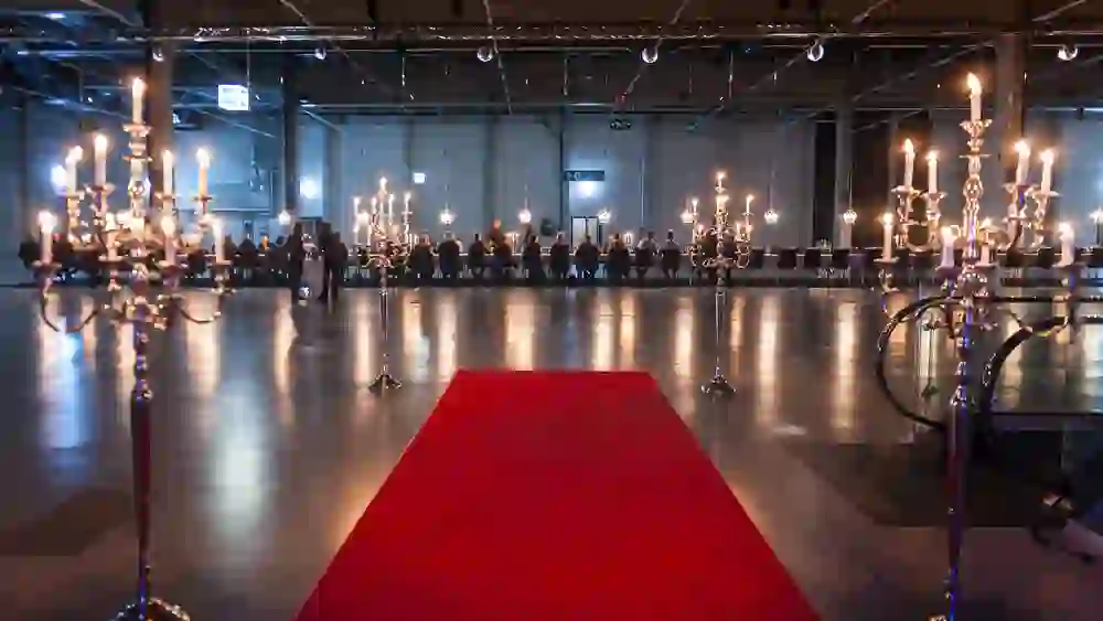 L'immagine mostra un'elegante sala per eventi con un tappeto rosso e candelabri d'atmosfera che creano un'atmosfera festosa ed esclusiva.