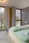Bright double room with large windows, simple wooden interior and a view of the greenery. The clear design and soft light create a calm, relaxed atmosphere for arriving and relaxing.