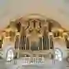 Magnificent organ with gold ornaments and angels. The room is flooded with light and solemn, creating an atmosphere of devotion and awe.