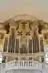 Magnificent organ with gold ornaments and angels. The room is flooded with light and solemn, creating an atmosphere of devotion and awe.