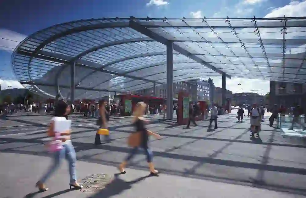 Sous la canopée moderne de la gare de Berne, l'activité est intense ; les gens pressés et les rencontres détendues se fondent sous l'architecture impressionnante.