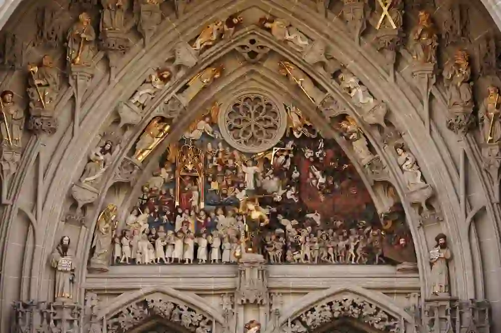 L'image montre le portail vivant et détaillé de la cathédrale de Berne, qui raconte des histoires gravées dans la pierre, un témoin muet de la foi et de l'art de Zs.