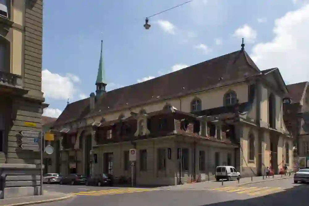 Sur l'image, on voit l'église française de Berne, avec son toit pointu et une tour de toit verte. Au premier plan, on voit un carrefour et on aperçoit des véhicules et des panneaux routiers.
