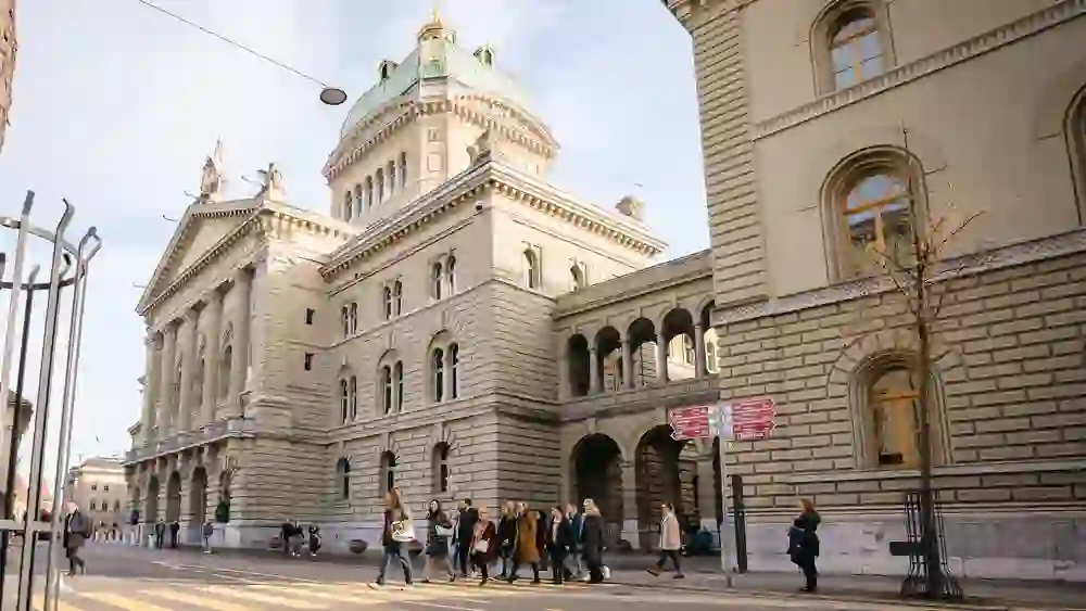 Eine Gruppe geht vor dem imposanten Bundeshaus in Bern entlang, eingetaucht in das historische Ambiente der Stadt, während sie mehr über das Jahr 1848 lernen, als Bern zur Bundesstadt wurde.
