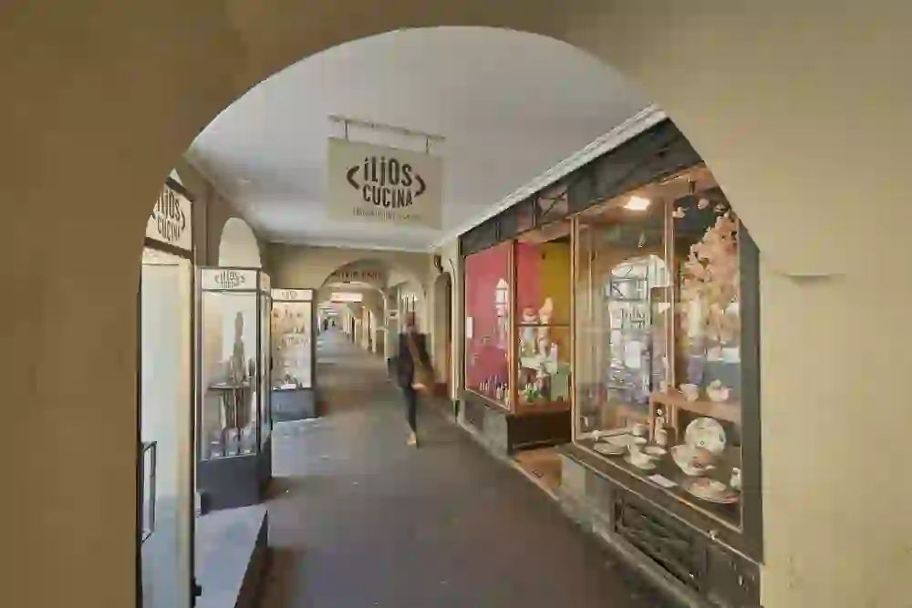 The picture shows the charming entrance to Iljos Cucina under the Bernese arcades. Even the shop window with its lovingly arranged ceramics and colourful accessories arouses curiosity about the diverse range inside. The covered arcade, the warm light and the creative design exude an inviting, lively atmosphere - an ideal place for discovering everything to do with tableware and more.