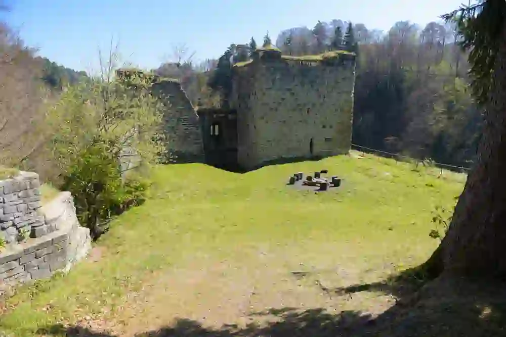 L'image présente les ruines de Grasburg, situées dans la paisible verdure de Schwarzenburg. Les murs de pierre en ruine qui se dressent sous le ciel bleu racontent des histoires silencieuses des temps passés et invitent à s'arrêter et à réfléchir dans un environnement historique paisible.