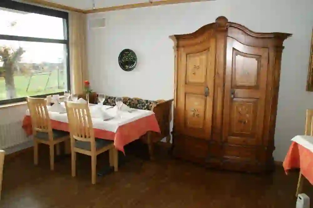 Der traditionelle Speisesaal im Hotel Restaurant Sternen mit rustikalem Schrank und gedeckten Tischen, der durch die Fenster einen Blick ins Grüne bietet, strahlt eine heimelige und einladende Atmosphäre aus.