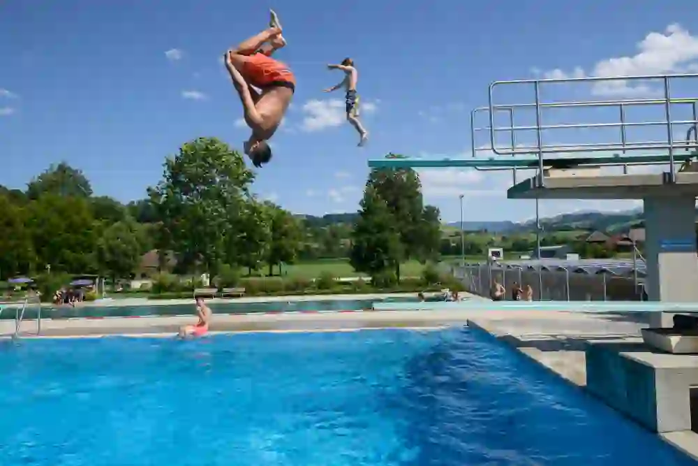Das Bild zeigt zwei junge Menschen, die von einem Sprungbrett springen.