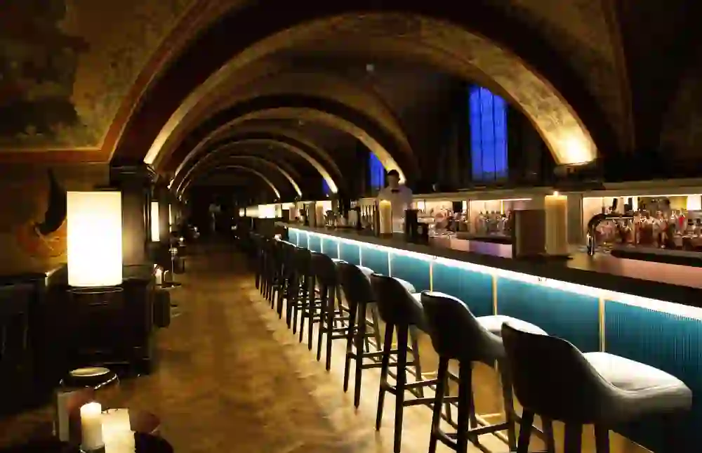 Das Bild zeigt die Bar des Kornhauskellers in Bern mit seinem beeindruckenden gewölbten Deckenfresko, stimmungsvoller Beleuchtung und einer langen Theke, die ein historisch-modernes Flair für einen eleganten Abend ausstrahlt.