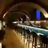 The picture shows the bar of the Kornhauskeller in Bern with its impressive vaulted ceiling fresco, atmospheric lighting and a long bar that exudes a historic-modern flair for an elegant evening.